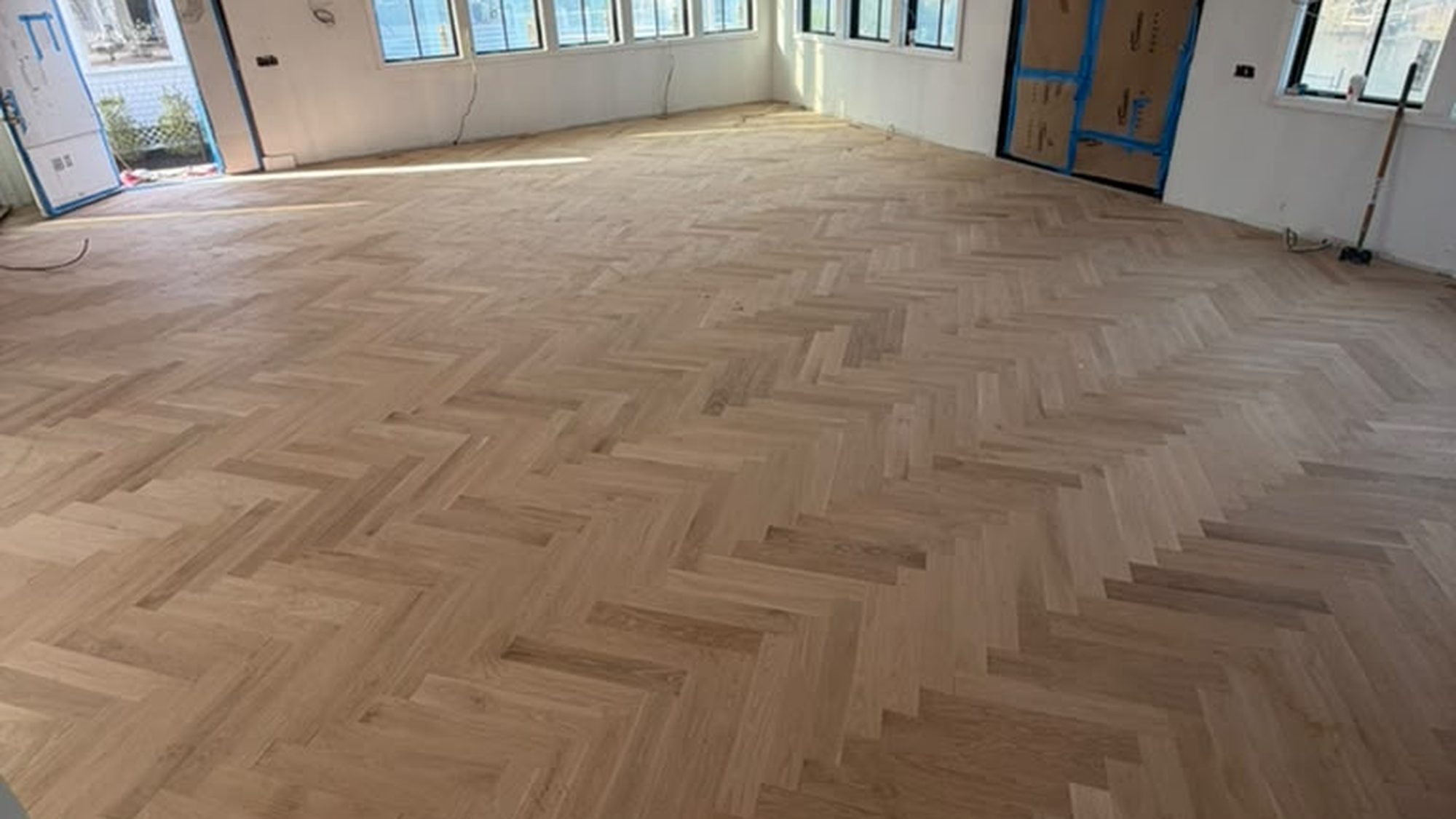 Finished white-oak herringbone hardwood floor in a bright, freshly renovated room