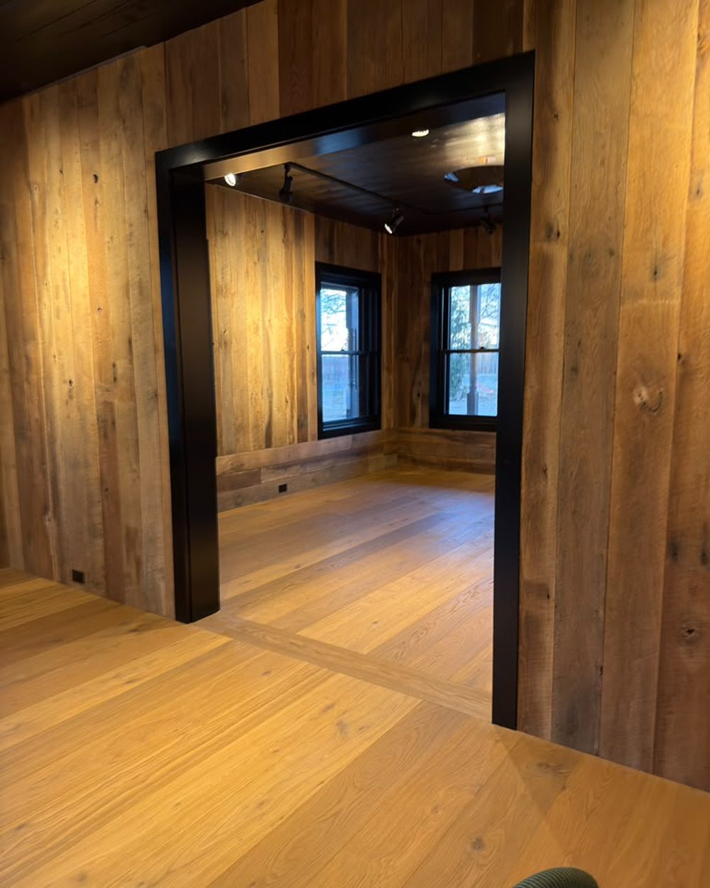 Wide-plank oak floor running through a black-trimmed doorway