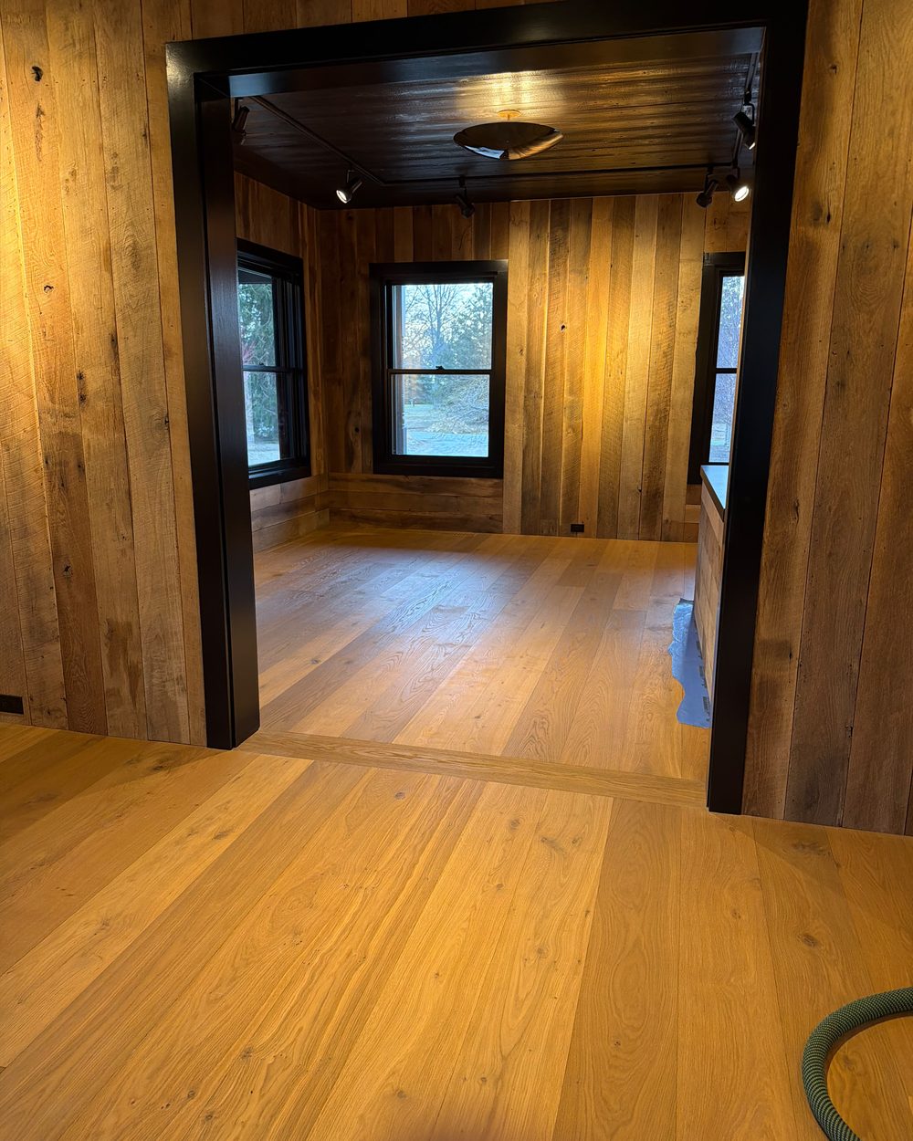 Wide-plank natural oak flooring in a reclaimed-wood paneled room