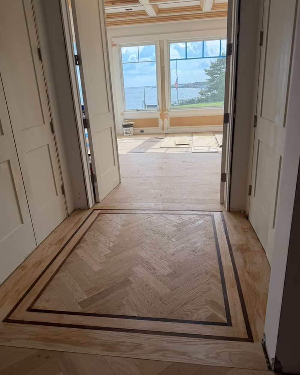 Custom herringbone inlay medallion with dark wood border in an entry hallway